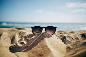 A pair of designer sunglasses rest atop the sand during a Lake Michigan summer vacation.