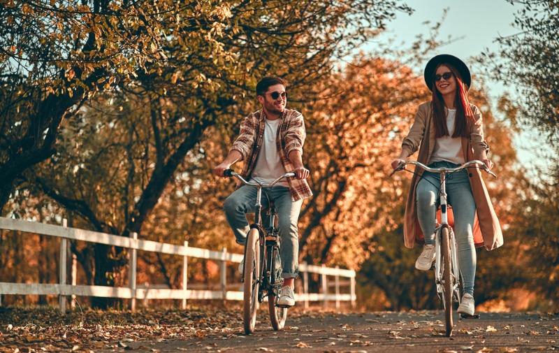 A young couple joyously rides their bikes amid the Michigan fall colors.