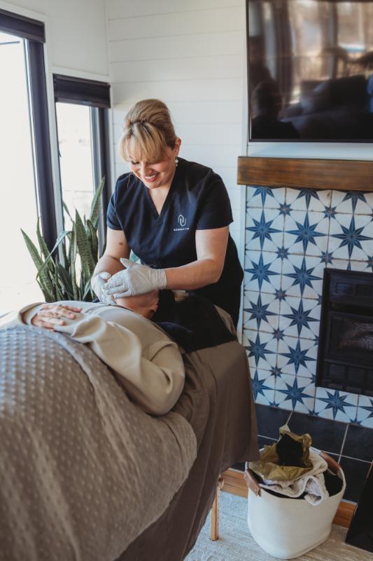 Spa person performing a face massage next to a fireplace